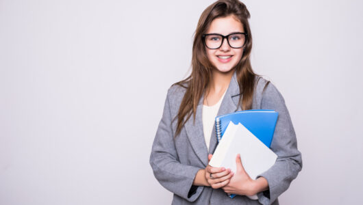 pretty-young-student-with-big-glasses-near-some-books-smiling-white-background